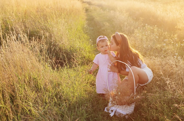 Two little sisters in summer field at sunset