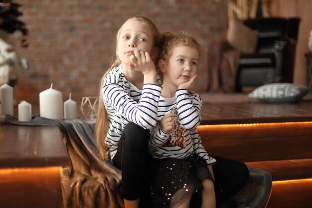 Two little sisters talk sitting in a cozy living room