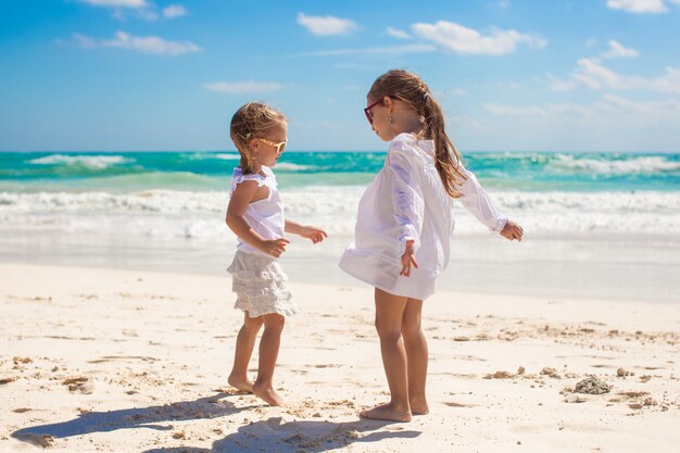 Two little sisters in white clothes have fun at tropical Mexico beach