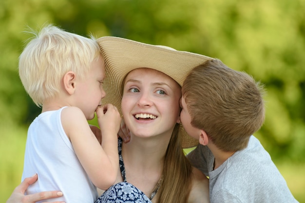 Two little sons hug the mother and kiss on the cheek 