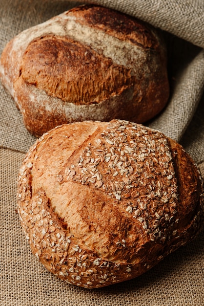 Two loaves of delicious rustic bread lying on a burlap-covered surface.