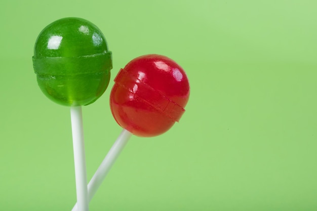 Two lollipops on a stick a closeup at the green background