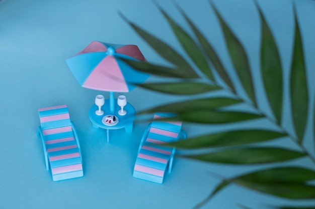 Two lounge chairs under an sun umbrella with two glasses and a dessert on the table