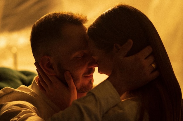 Photo two lovers kissing on neon light background woman touching face her boyfriend when kisses indoors