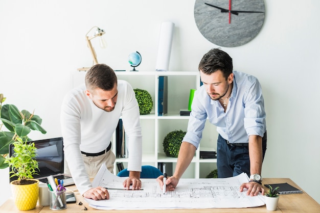 Photo two male architect preparing blueprint in office