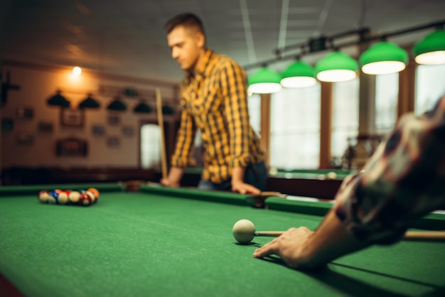 Two male billiard players with cue at the table