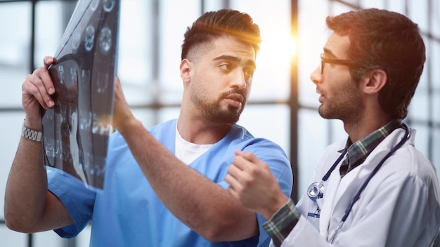 Два врача-мужчины смотрят на рентген головного мозга