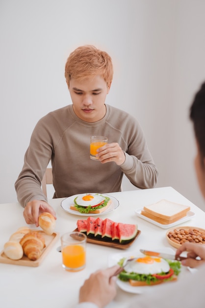 Two male friends eating breakfast at home in morning.