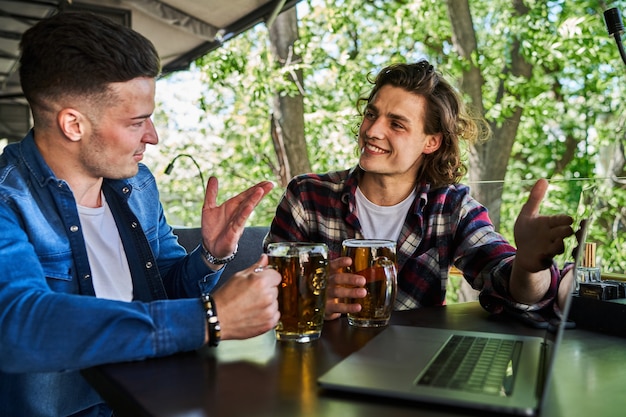 Photo two male friens watching football in a pub and drinking beer.