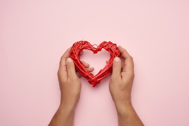 Two male hands holding a red wicker heart, love concept