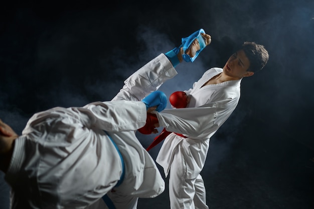 Due karateka maschi in kimono bianco e guanti, combattimento in azione. combattenti in allenamento, arti marziali, gare di combattimento