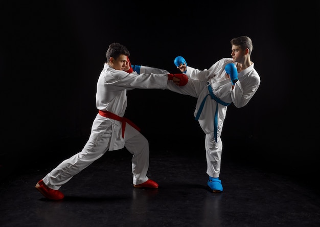 Two male karatekas in white kimono and gloves, strike in action. Fighters on workout, martial arts, fighting competition