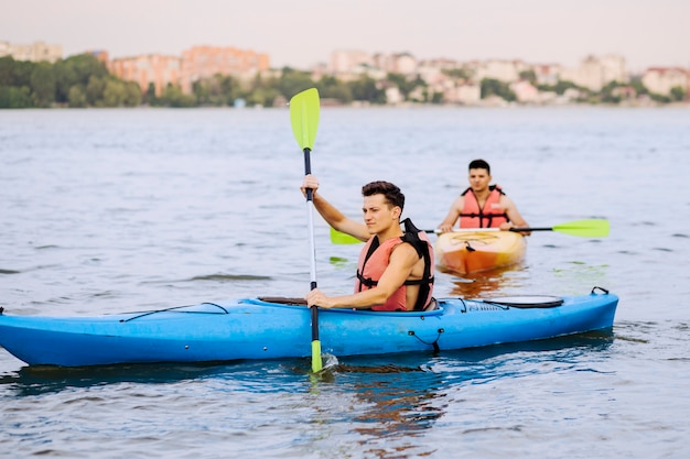 Two male paddling kayak on lake