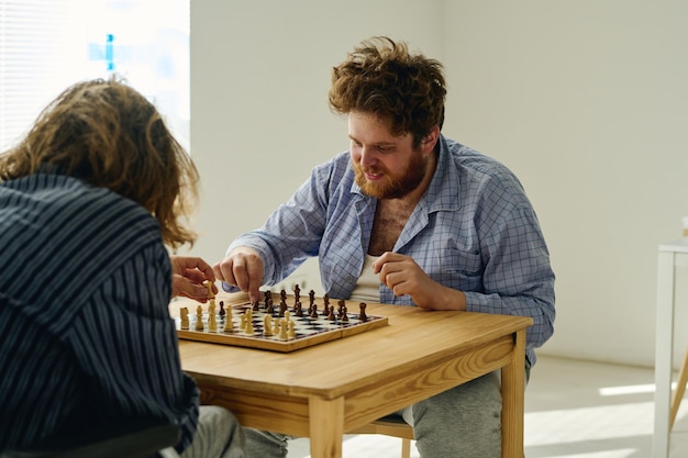 Two male patients of mental hospital moving pawns along chessboard