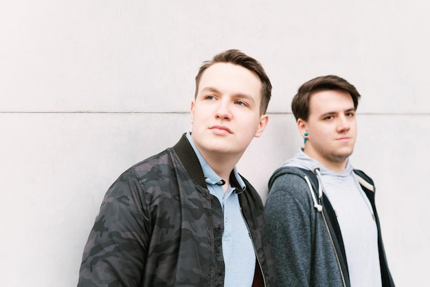 Photo two male teenage friends or brothers leaning against wall