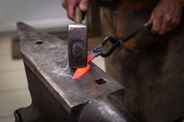 Two man hands are manufacturing a steel knife