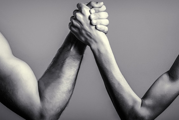 Photo two man's hands clasped arm wrestling strong and weak unequal matcharm wrestling arm wrestling thin hand and a big strong arm in studio black and white