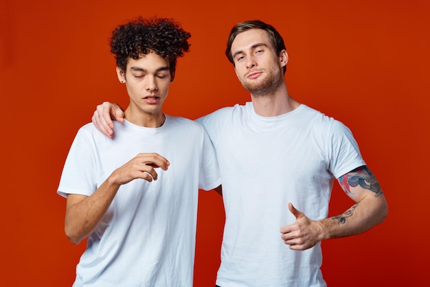 Двое мужчин в белых футболках веселые эмоции жесты рук дружба объятия