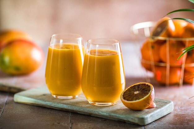 Due lassi di mango o latte di kesar in bicchieri bevanda fredda ayurvedica salutare indiana con mango freschezza lassi fatta di yogurt acqua spezie frutta e ghiaccio