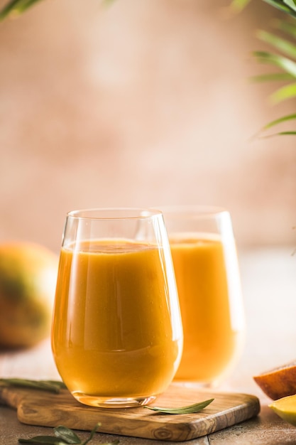 Two mango lassi or kesar milk in glasses Indian healthy ayurvedic cold drink with mango Freshness lassi made of yogurt water spices fruits and ice