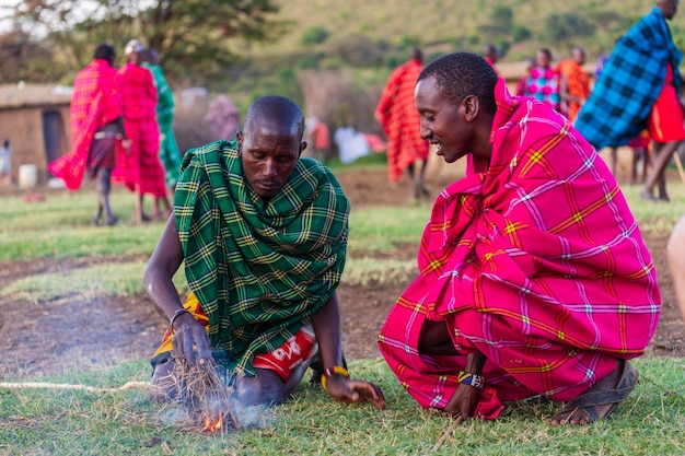 Two Masai men making a fire traditionally in Masai village. Masai Mara, Kenya