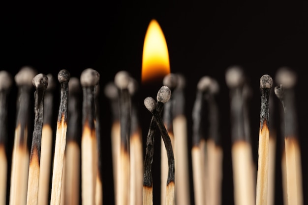 Two matches with a small fire above them standing close to each other