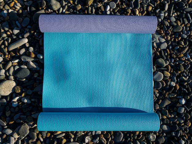 Two mats for yoga, Pilates or fitness lie on the rocks by the sea.