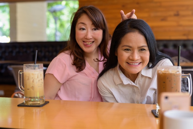 Two mature Asian women together hanging out at the coffee shop