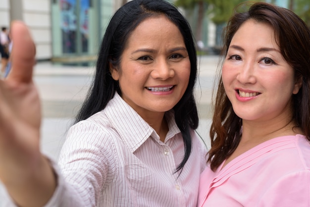 Two mature Asian women together outside the mall in Bangkok city