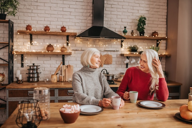 Two mature grey-haired positive ladies having conversation