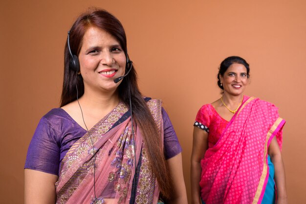 two mature Indian women wearing Sari Indian traditional clothes together with headset