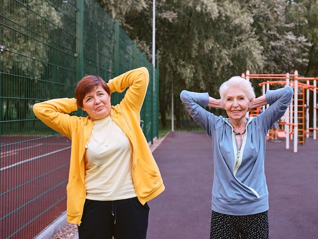 Foto due donne mature che fanno esercizi sportivi nel concetto di stile di vita sano del parco