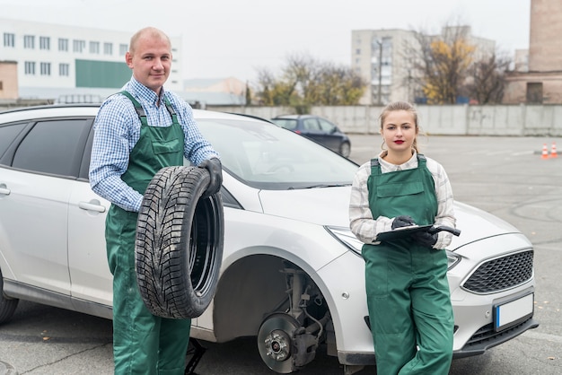 Two mechanics examining brake disk in car