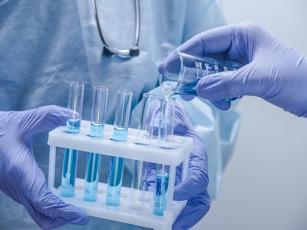 Два ученых-медика в защитной одежде держат пробирки в лаборатории