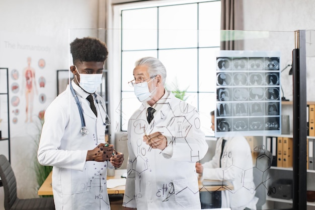 Two medical specialists in masks having meeting at room