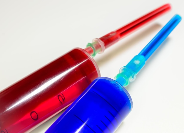 Two medical syringes one with the vaccine and one with the test blood on white background.