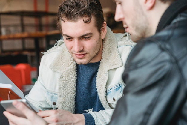 two men are sitting in a library and one has a jacket on