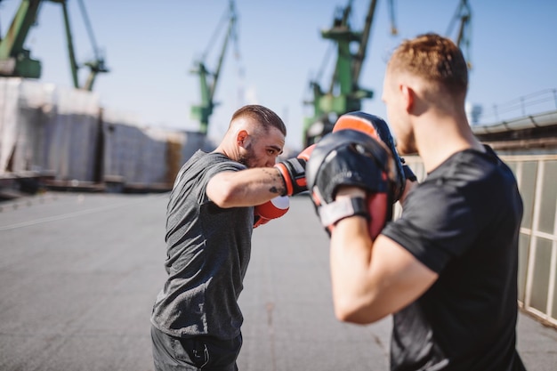 2人の男性が市内の工業地帯の建物の屋上でボクシングのトレーニングをし、スパーリングと格闘を行っている