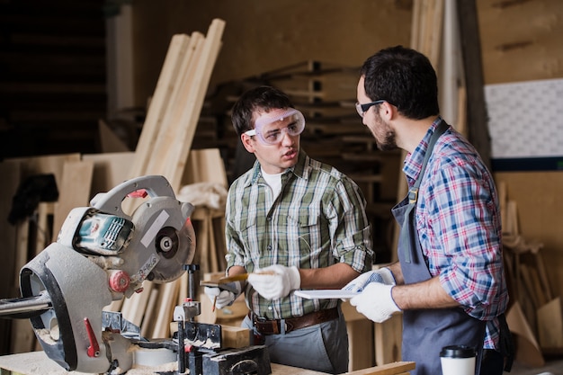 Photo two men builder with circular saw having a conversation