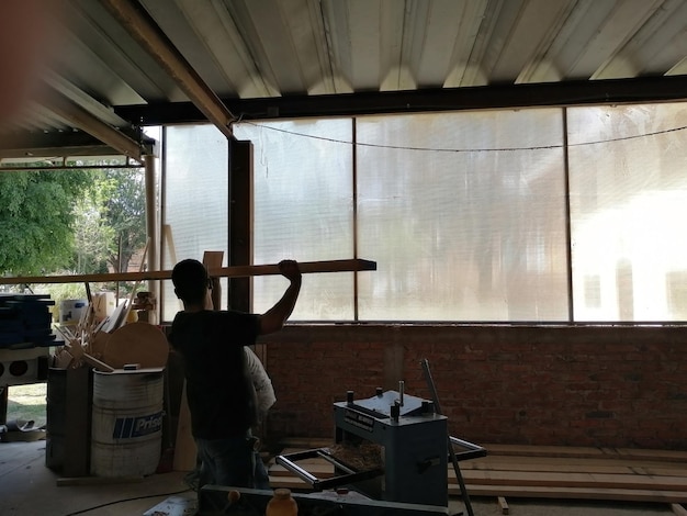 Two men carrying a wooden board working in a carpentry shop