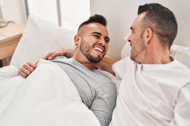 Photo two men couple lying on bed hugging each other at bedroom