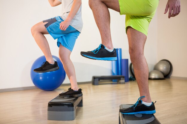 Two men doing step aerobic exercise on stepper