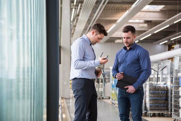 Two men in factory shop floor examining product