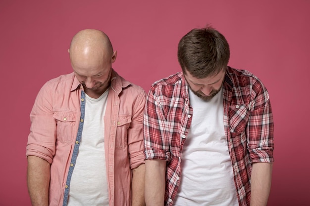 Two men feel guilty and stand with their heads down. isolated\
on a red background.