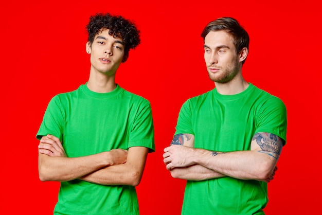 Two men in green tshirts stand next to communication friendship high quality photo