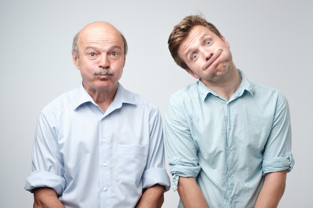 Two men grimacing, inflating cheeks, holding breath