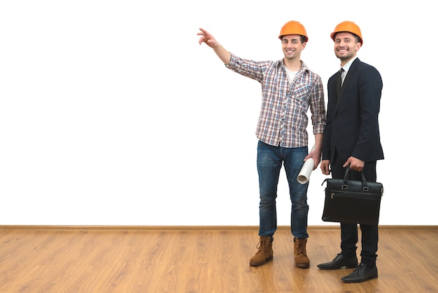 The two men in helmets gesture on the white wall background