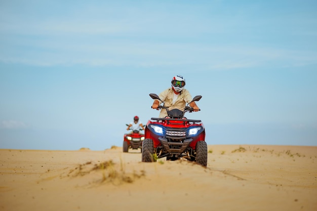 Two men in helmets ride on atv, action view