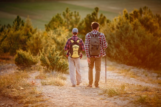 Two men hikers enjoy a walk in nature sunset time in summer