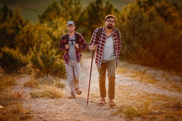 두 남자 등산객은 여름에 자연 일몰 시간에서 산책을 즐깁니다.